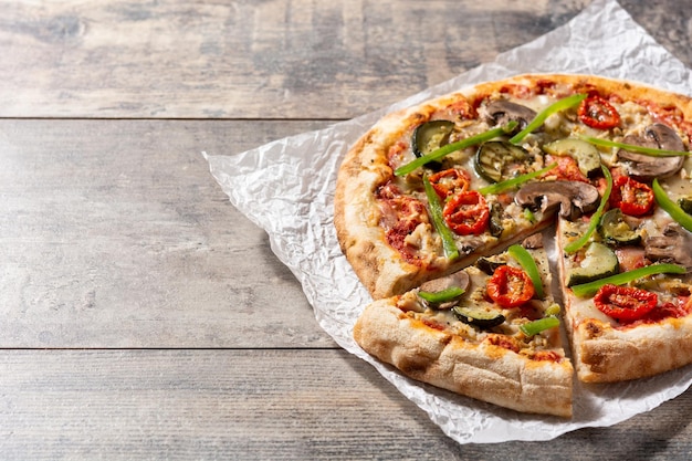 Pizza vegetariana con zucchine, pomodori, peperoni e funghi su tavola di legno Spazio di copia