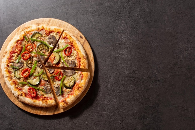 Pizza vegetariana con zucchine pomodoro peperoni e funghi su pietra nera