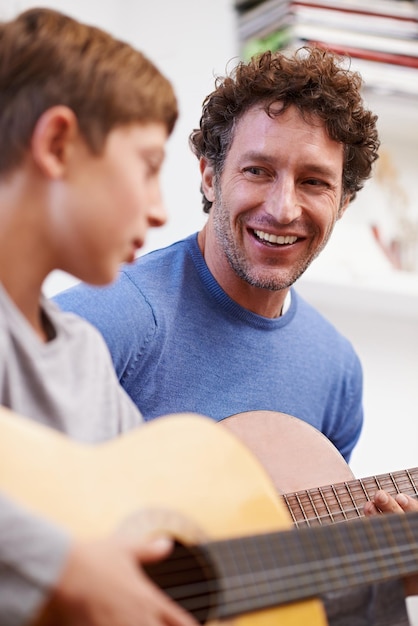 Pizzicare con orgoglio Inquadratura di un padre che insegna la chitarra a suo figlio