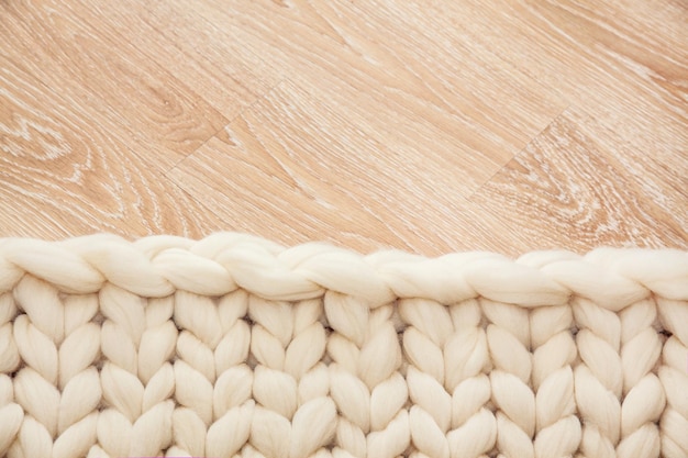 Plaid lavorato a maglia di grande maglia in lana merino su pavimento in legno.