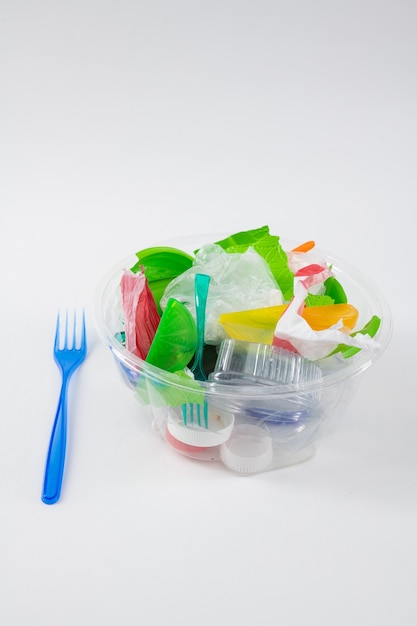 Plastica pericolosa. Contenitore trasparente trasparente pieno di spazzatura e immondizia con una forchetta preparata nelle vicinanze