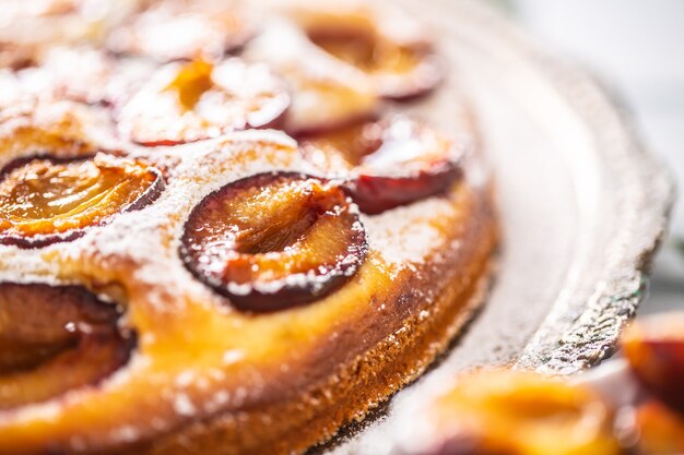 Plumcake casalingo in piatto d'annata sulla tavola di legno. Torta di prugne con zucchero a velo.