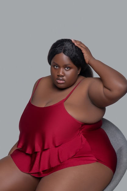 Plus size giovane donna afro-americana in biancheria intima rossa seduta su una sedia