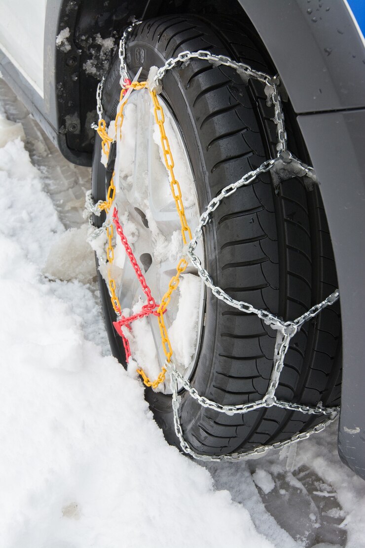Pneumatico con catene da neve montate nel giorno di neve invernale