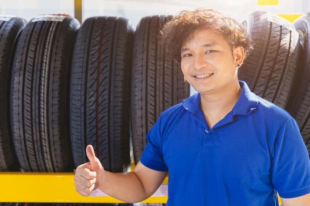 Pneumatico per auto sullo scaffale con agente di vendita felice di fornire assistenza nel pneumatico per veicoli di qualità del negozio di pneumatici consigliato