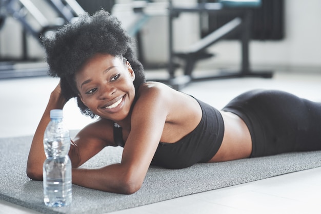 Pochi minuti e mi riprenderò. La donna afroamericana con i capelli ricci e in abiti sportivi ha una giornata di fitness in palestra