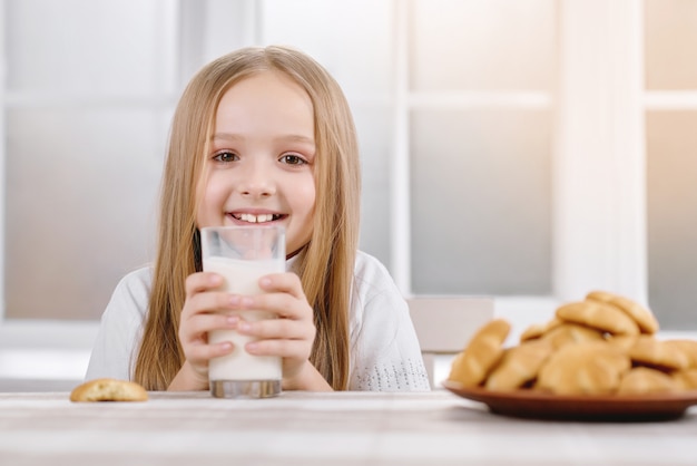 Poco carino mantiene il bicchiere di latte