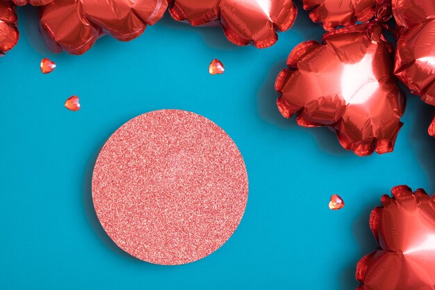 Podio glitterato o piedistallo e confezione regalo con palloncini a forma di cuore rosso su sfondo turchese Tema di San Valentino