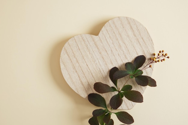 Podio in legno a forma di cuore e ramo con foglie verdi e fiori