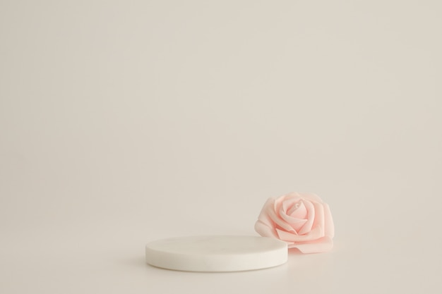 Podio in marmo bianco su fondo bianco con fiori rosa. Podio per prodotto, presentazione cosmetica. Mock up creativo. Piedistallo o piattaforma per prodotti di bellezza.
