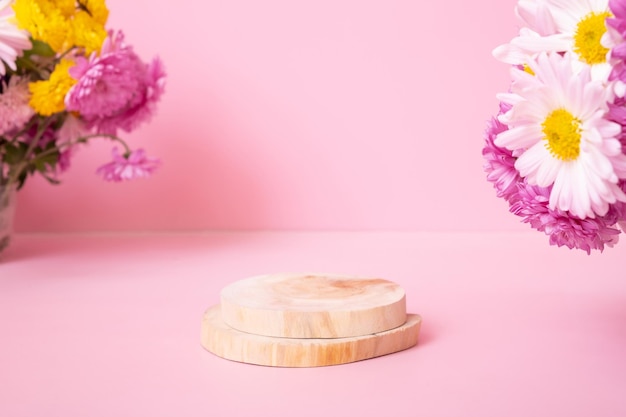 Podio o piedistallo in legno con fiori di crisantemo su sfondo rosa Mockup per i tuoi prodotti cosmetici