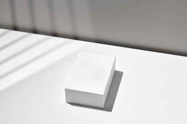 Podio vuoto bianco su sfondo tavolo bianco display Muro grigio vuoto Modello per la pubblicità
