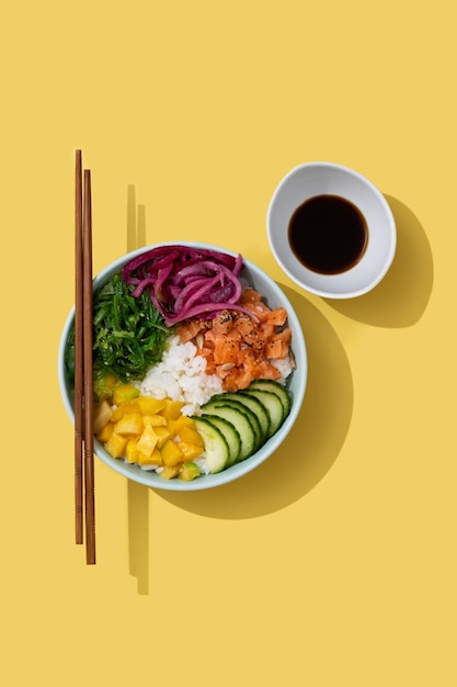 Poke bowl con riso salmonecetriolomangoonionwakame insalata semi di papavero e semi di girasoli su sfondo giallo