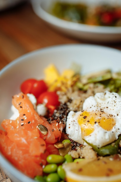 Poke bowl con salmone, spinaci, quinoa, cetriolo e ravanello. Concetto di mangiare pulito.