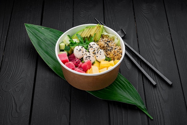 Poke bowl con tonno riso avocado cetriolo crema di formaggio e mango su sfondo scuro