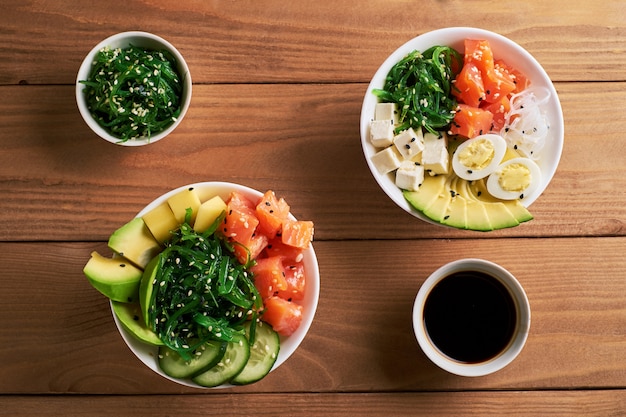 Poke Bowl crudo biologico con riso, avocado, salmone, salsa di soia due piatti