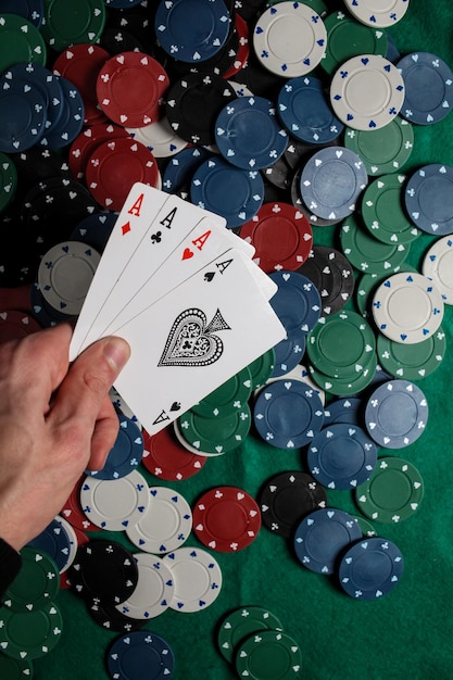 Poker Senior. Il giocatore ha in mano quattro carte da gioco, quattro assi. Sfondo di fiches del casinò