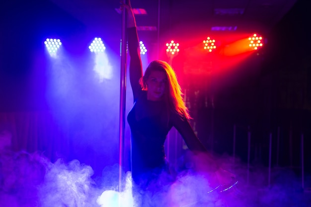 Pole dance. Giovane donna sexy snella che balla su un palo all'interno di una discoteca