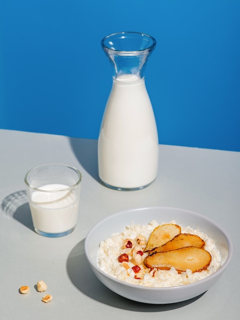 polenta con fettine di pera fresca, mandorle e nocciole tritate. Concetto di colazione sana. Tavolo in legno bianco. Vista del primo piano. Ciotola su tessuto grigio.