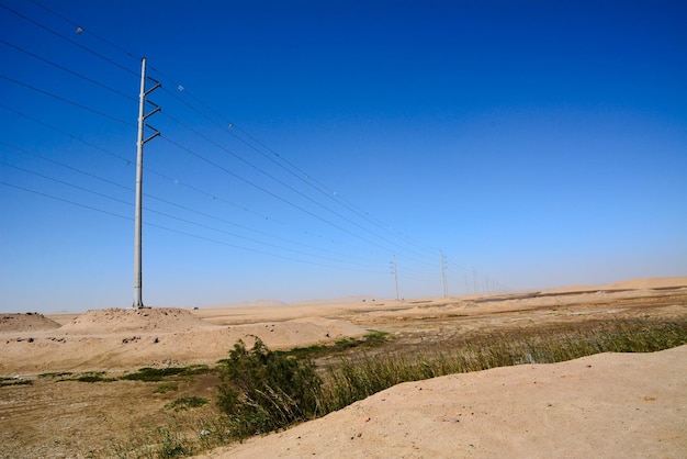 Poli torreggianti ad alta tensione di elettrificazione in prospettiva nel deserto