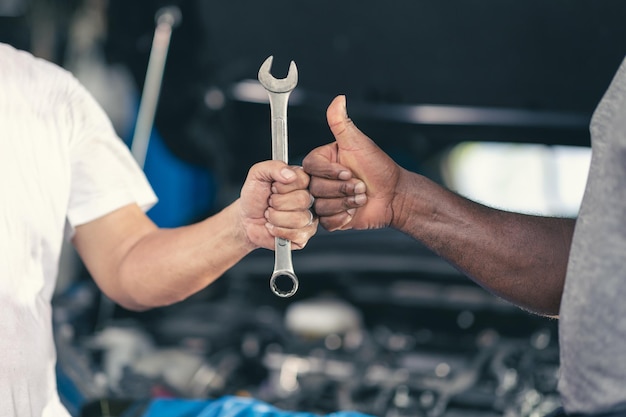 Pollice alzato del meccanico del lavoratore del garage con lo strumento Lavoro finito Lavoro fatto buona riparazione concetto di servizio del motore dell'automobile di riparazione dell'automobile