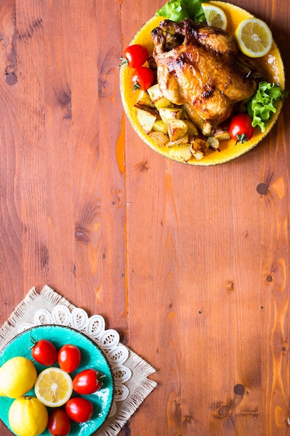 Pollo al forno casalingo con il limone e le patate su un fondo di legno