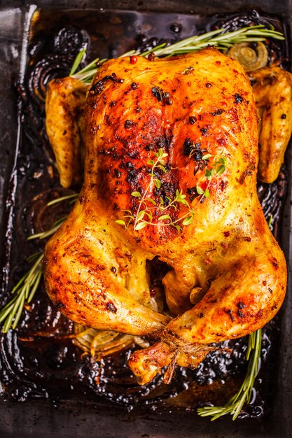 Pollo al forno con spezie e cipolle in un piatto di vetro, vista dall'alto.