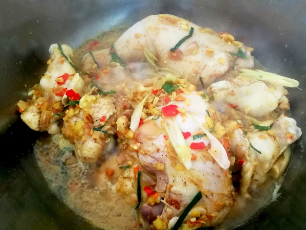 Pollo al vapore in pentola con erbe tailandesi close up