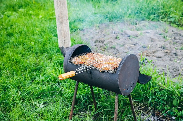 Pollo alla griglia all'aperto. Barbecue in fiamme in estate. Buon tempo. Cucinare la carne nella natura.