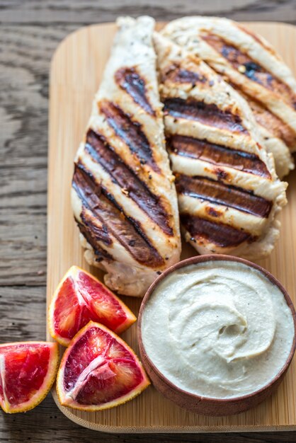 Pollo alla griglia con salsa tahini sul bordo di legno