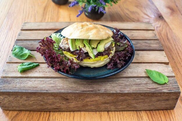 Pollo alla griglia e panino di avocado sulla tavola di legno