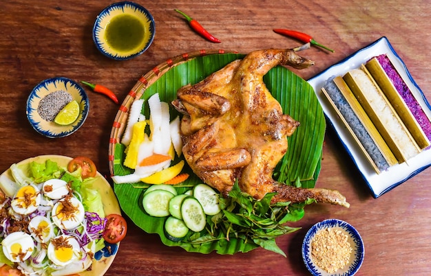 Pollo alla griglia in stile vietnamita con riso colorato in bambù e uova sode sulla tavola di legno