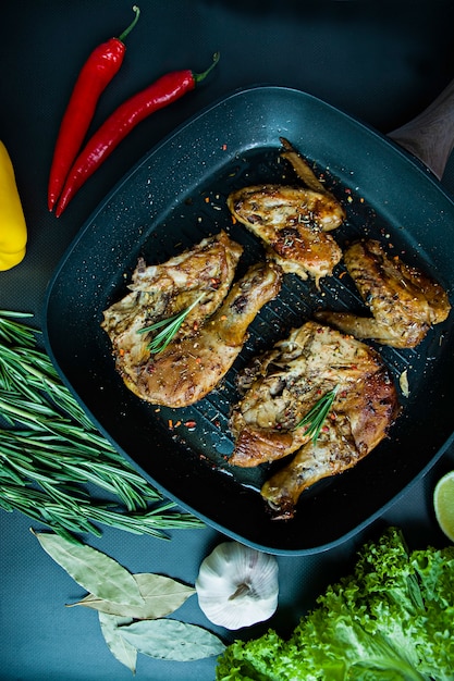 Pollo alla griglia in una griglia padella verdure su uno sfondo scuro.