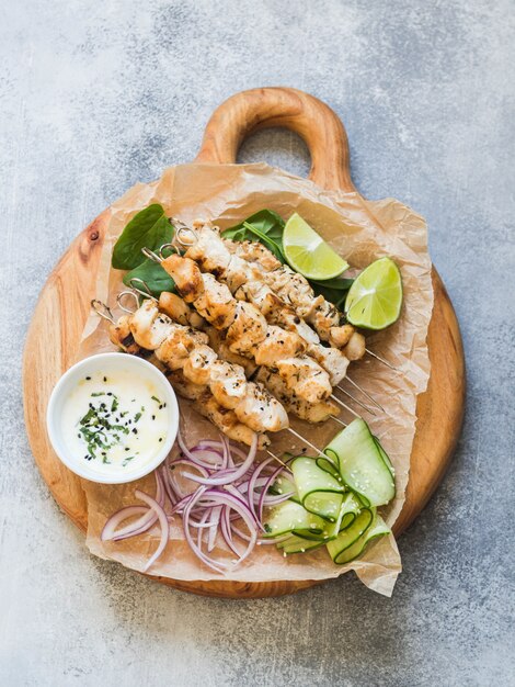 Pollo alla griglia su spiedini di metallo su foglie di spinaci