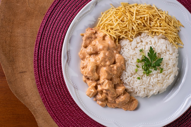 Pollo alla Stroganoff accompagnato da riso, insalata e paglia di patate.