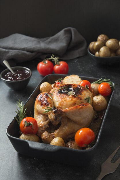 Pollo arrostito con la patata sulla tavola nera.