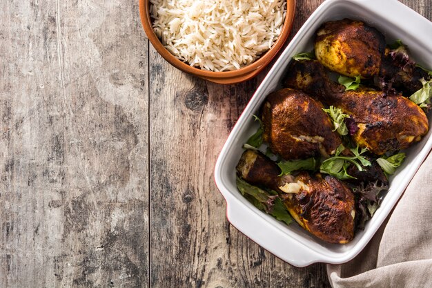 Pollo arrostito di tandoori con riso basmati sulla tavola di legno. Vista dall'alto.