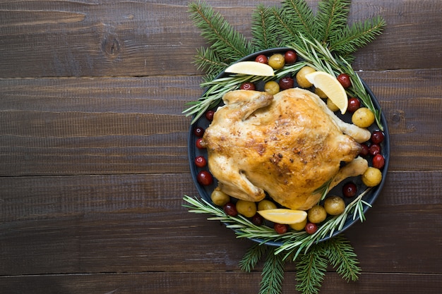 Pollo arrostito Natale con spezie e rosmarino sulla tavola di legno.