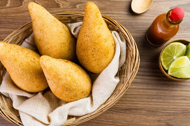 Pollo Coxinha noto come Coxinha in Brasile Servito nel cestino con spezie come limone e pepe sul lato Tavolo di legno sullo sfondo Spuntino tradizionale brasiliano Messa a fuoco selettiva