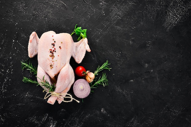 Pollo crudo con verdure e spezie Barbecue su sfondo di pietra nera Vista dall'alto Spazio libero per la copia