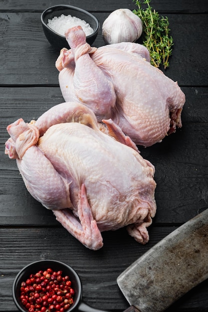 Pollo crudo fresco con gli ingredienti delle spezie delle erbe, sulla tavola di legno nera