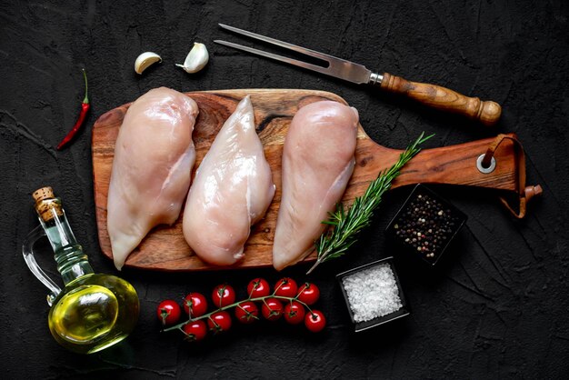 Pollo crudo su un tagliere con erbe e spezie.