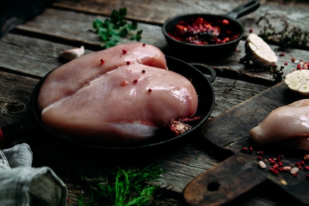 Pollo crudo su un tavolo di legno con spezie