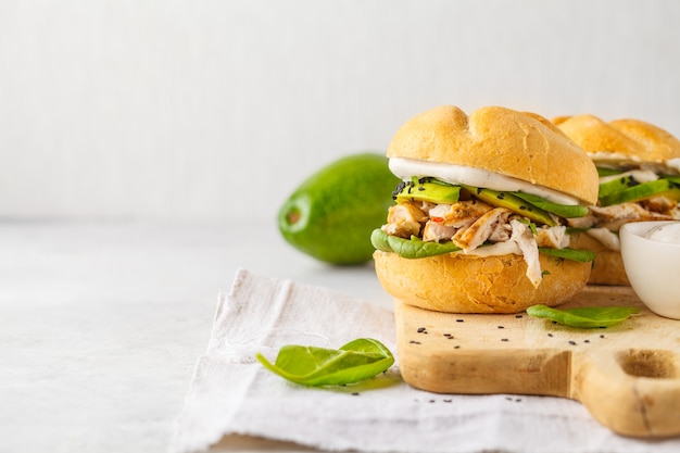 Pollo e avocado hamburger alla griglia sul bordo di legno, spazio della copia.