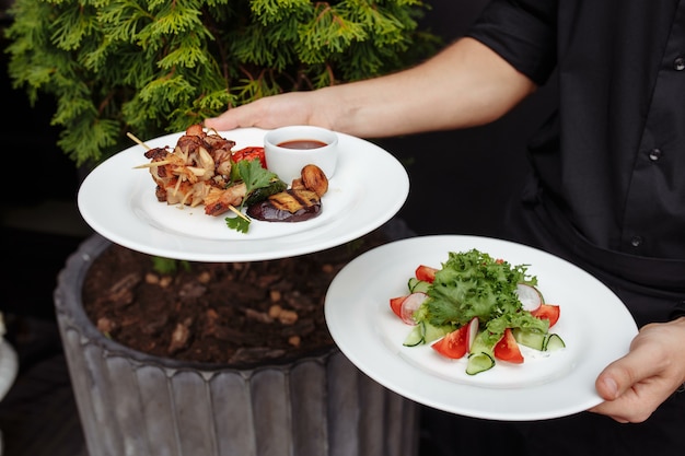 Pollo e insalata alla griglia nelle mani di un cameriere