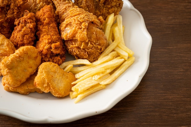 pollo fritto con patatine fritte e pepite sul piatto - cibo malsano