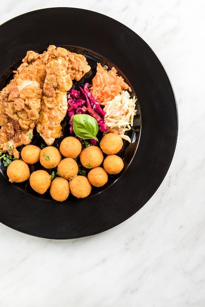 Pollo fritto con polpette di patate e porzione di ristorante di insalata