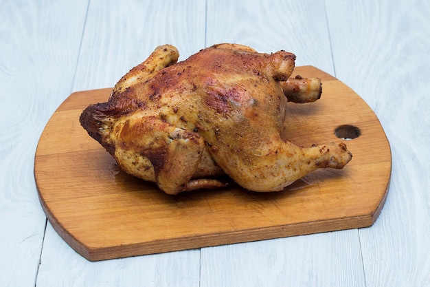 Pollo fritto intero in spezie su un vassoio di legno