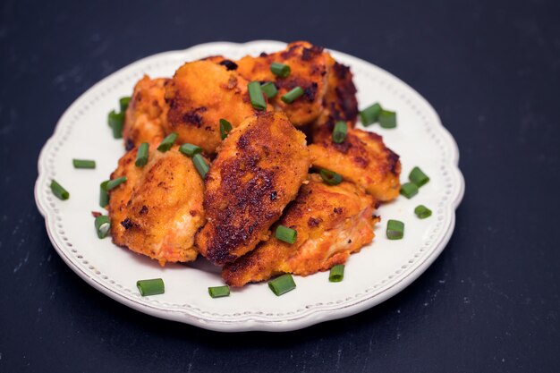 Pollo fritto sul piatto bianco su superficie di legno