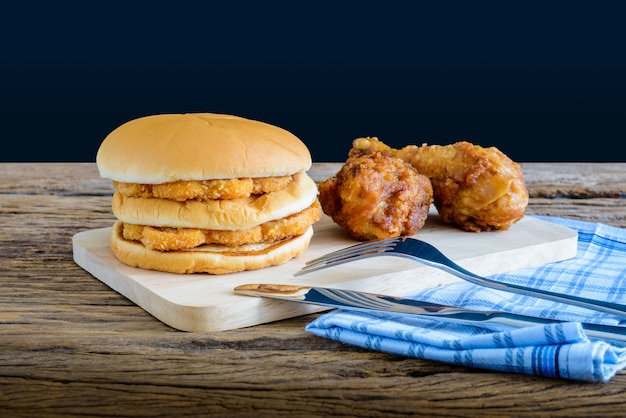 Pollo hamburger e pollo fritto sul tagliere di legno con coltello e forchetta, tovagliolo